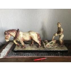 Mooi gipsenbeeld van ploegend paard en boer.